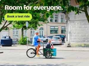 Een advertentie van het demomerk: een ouder op een bakfiets in een straat in de stad onder de kop Room for everyone, met een knop Book a test ride.