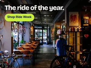 Een etalagesticker: de binnenkant van een fietsenwinkel onder de kop The ride of the year, met een knop Shop Ride Week.