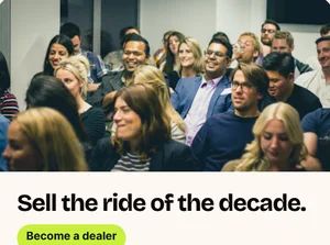 Een uitnodiging voor een dealerwebinar: een volle zaal onder de kop Sell the ride of the decade, met een knop Become a dealer.